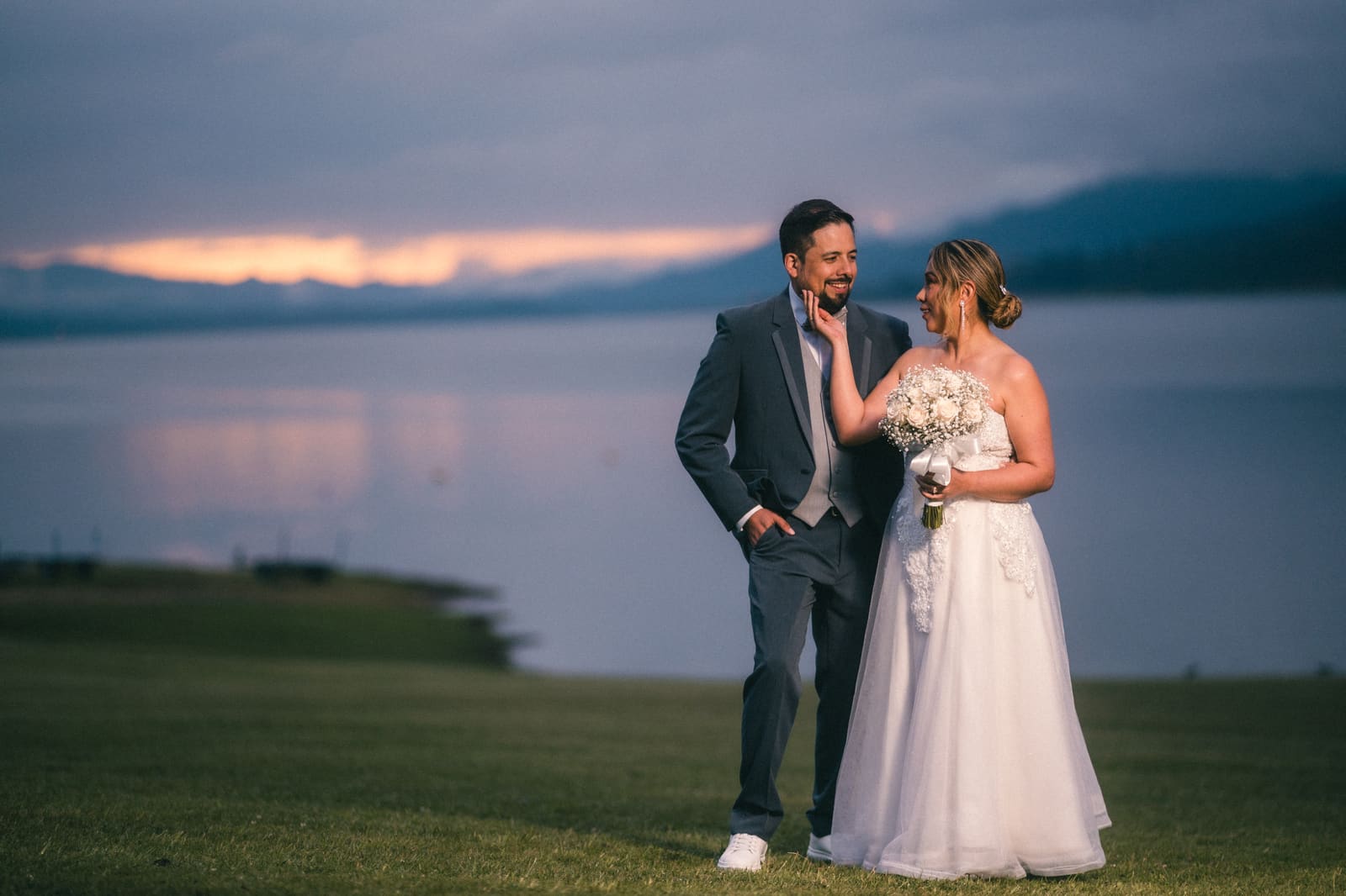 Pareja de novios abrazada al atardecer en un paisaje amplio